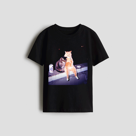 A black t-shirt with a printed image of two cats sitting on a ledge, one orange and one gray, with a can of beer next to them.