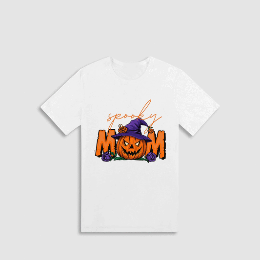 A white t-shirt with a Halloween-themed graphic design. The design features a pumpkin with a witch's hat on it, surrounded by the text "spooky mom" in orange and purple colors.