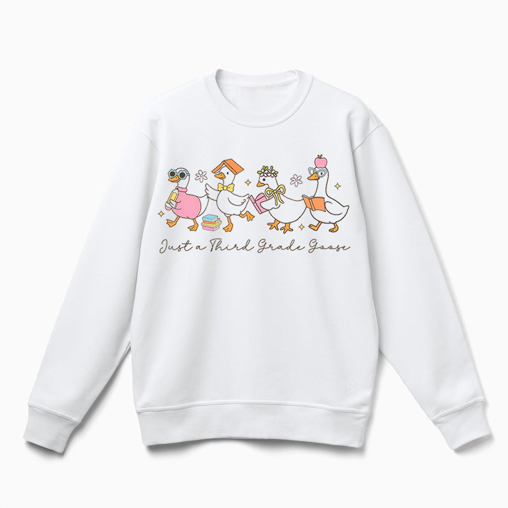 A white sweatshirt with a graphic design featuring a group of cartoon ducks, along with the text "Just a Third Grade Goose" printed on it.
