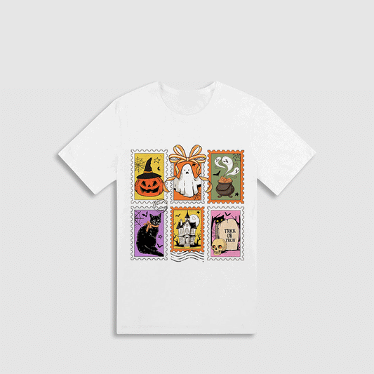 A white t-shirt with a graphic design featuring various Halloween-themed illustrations, including a jack-o-lantern, a witch, a ghost, a cat, a castle, and a witch's broomstick.