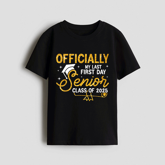 The image is a black t-shirt with a graphic design that says "OFFICIALLY MY LAST FIRST DAY SENIOR CLASS OF 2025" printed on it.