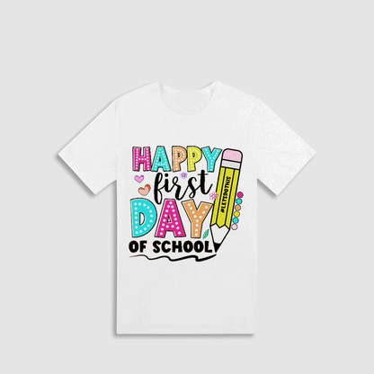A white t-shirt with a colorful graphic design that says "HAPPY FIRST DAY OF SCHOOL" and includes various school-related elements such as a pencil, hearts, and a book.