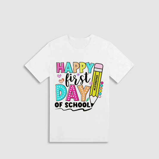 A white t-shirt with a colorful graphic design that says "HAPPY FIRST DAY OF SCHOOL" and includes various school-related elements such as a pencil, hearts, and a book.
