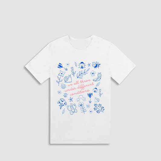A white t-shirt with a printed design featuring various blue and white illustrations, along with the text "we all thrive under different conditions" printed on it.