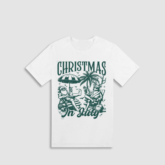 A white t-shirt with a graphic design featuring a Christmas scene with Santa Claus and palm trees, along with the text "Christmas In July".