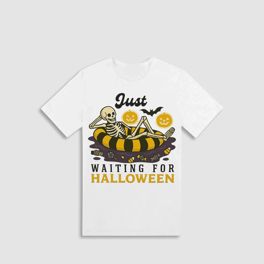 A white t-shirt with a Halloween-themed graphic design. The design features a skeleton lying on a striped float, surrounded by jack-o-lanterns and bats. The text on the t-shirt reads "Just waiting for Halloween".