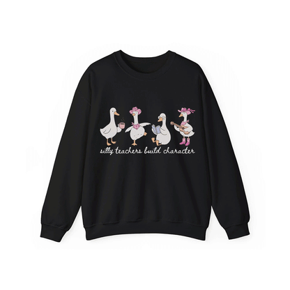 A black sweatshirt with a graphic design featuring four cartoon ducks, each with a unique hat and accessory, and the text "silly teachers build character" below them.