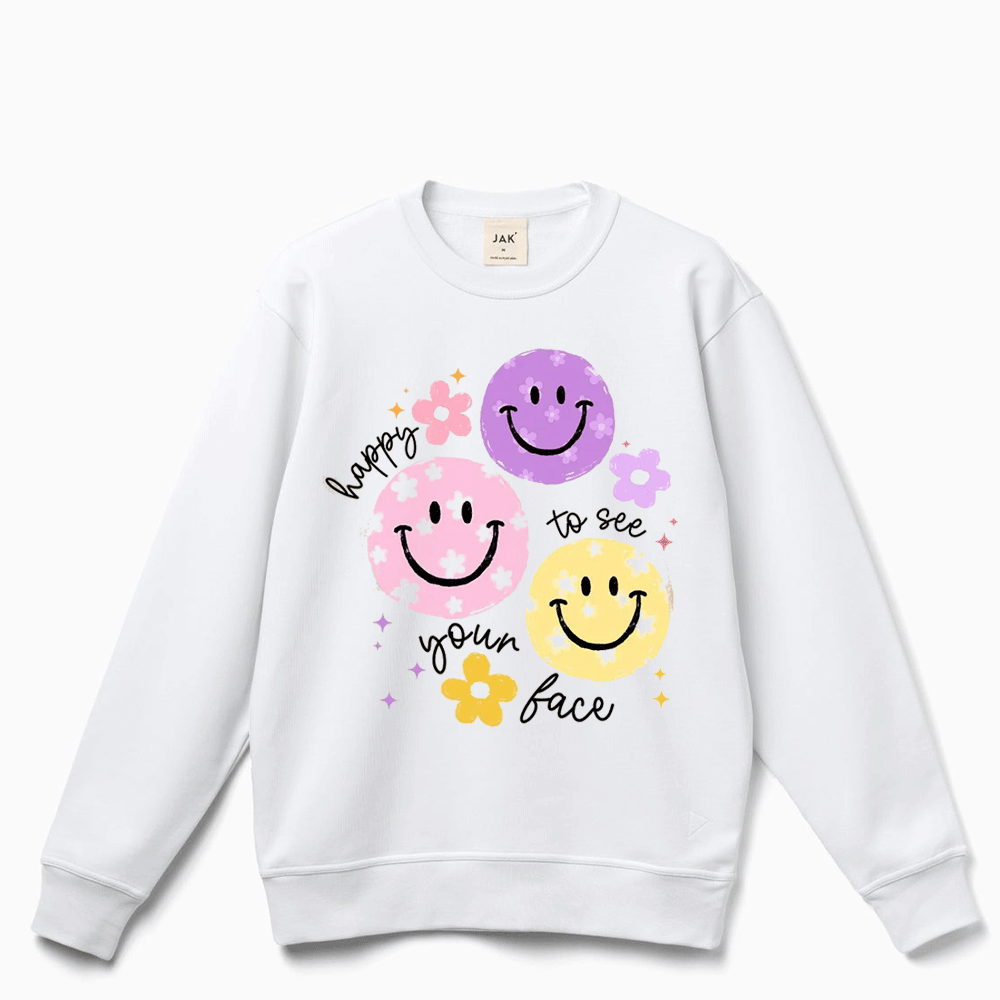 A white sweatshirt with a graphic design featuring three smiling faces and the text "happy to see your face" written around them.