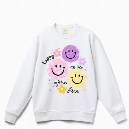 A white sweatshirt with a graphic design featuring three smiling faces and the text "happy to see your face" written around them.
