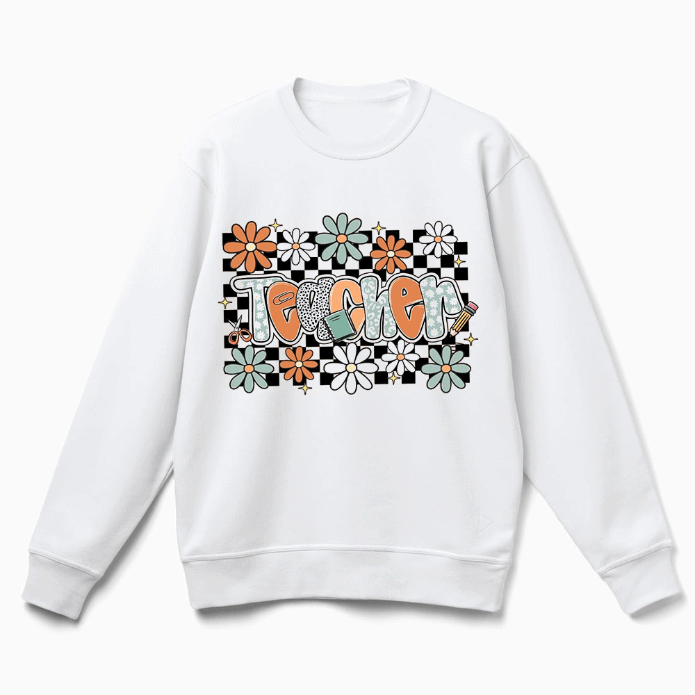 A white sweatshirt with a graphic design featuring the word "Teacher" surrounded by colorful flowers and checkered patterns.