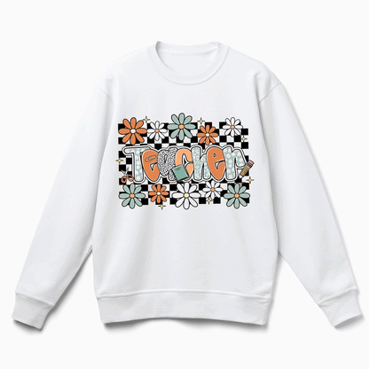 A white sweatshirt with a graphic design featuring the word "Teacher" surrounded by colorful flowers and checkered patterns.