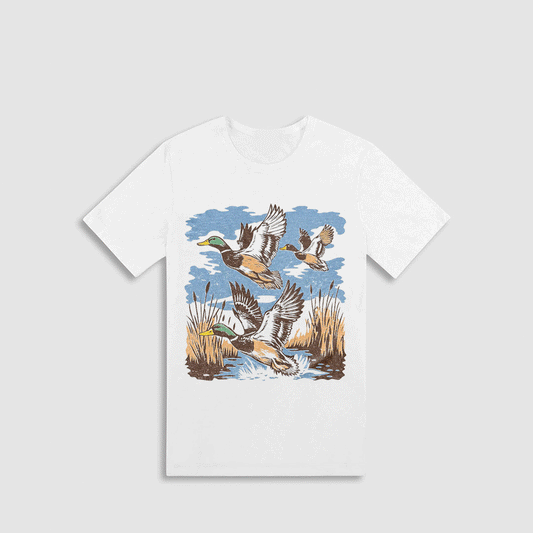 A white t-shirt with a graphic design depicting ducks flying over a body of water.