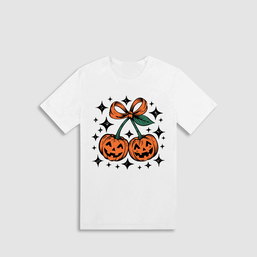 A white t-shirt with a graphic design featuring two jack-o'-lanterns and a bow, surrounded by stars.