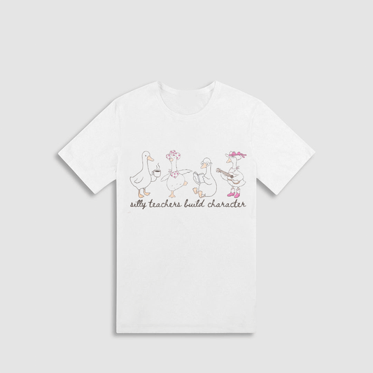 A white t-shirt with a graphic design featuring a group of cartoon ducks and the text "silly teachers build character".
