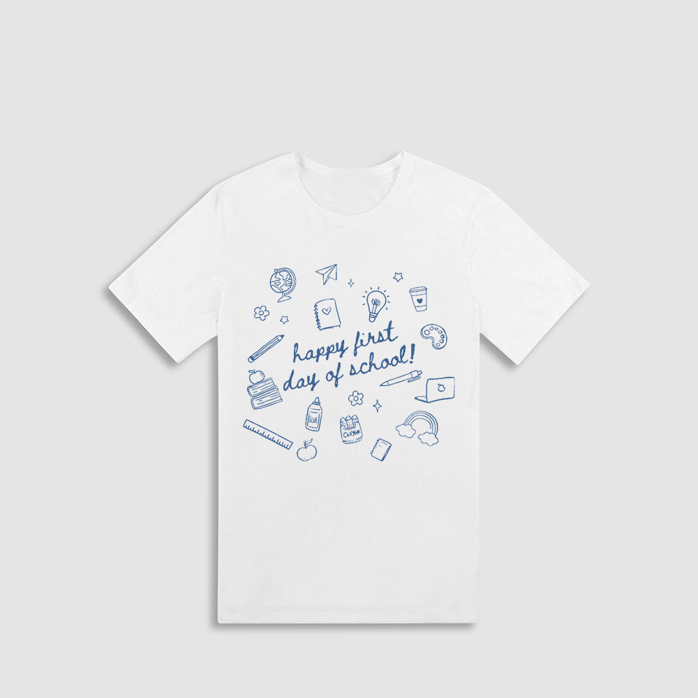 A white t-shirt with a graphic design featuring various school-related items such as a globe, pencil, book, and other school supplies, along with the text "happy first day of school!"