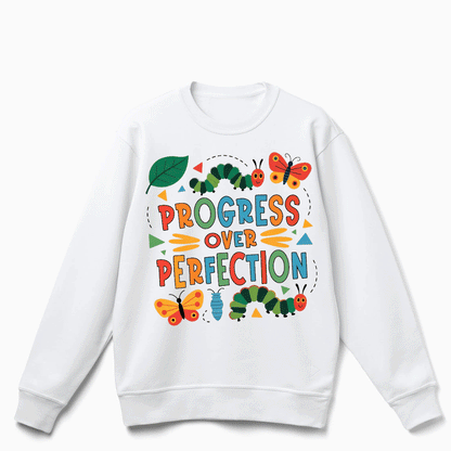 A white sweatshirt with a colorful graphic design featuring butterflies, caterpillars, and the text "PROGRESS OVER PERFECTION".