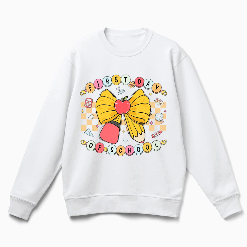 A white sweatshirt with a colorful graphic design featuring a yellow bow, an apple, and various school-related icons.